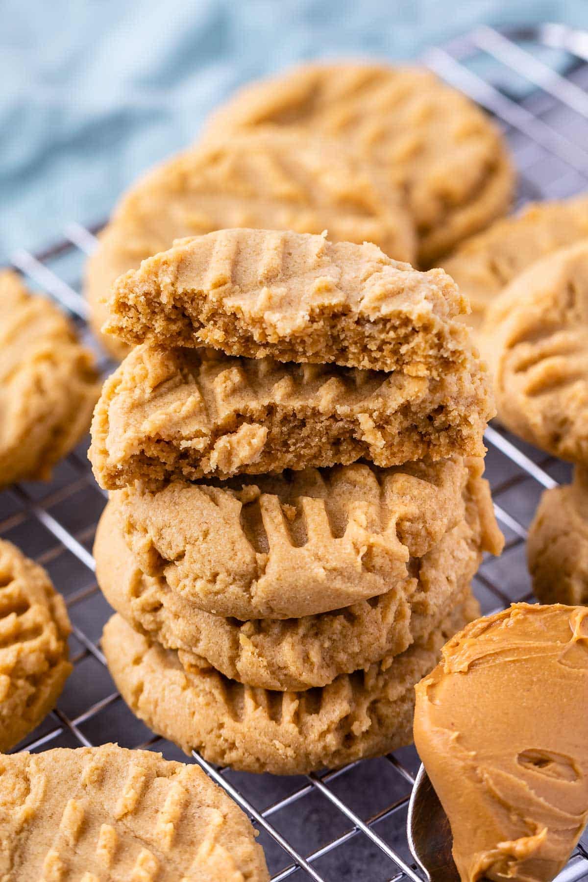 stack of 3 peanut butter cookies with 2 halves on top all sitting on a rack