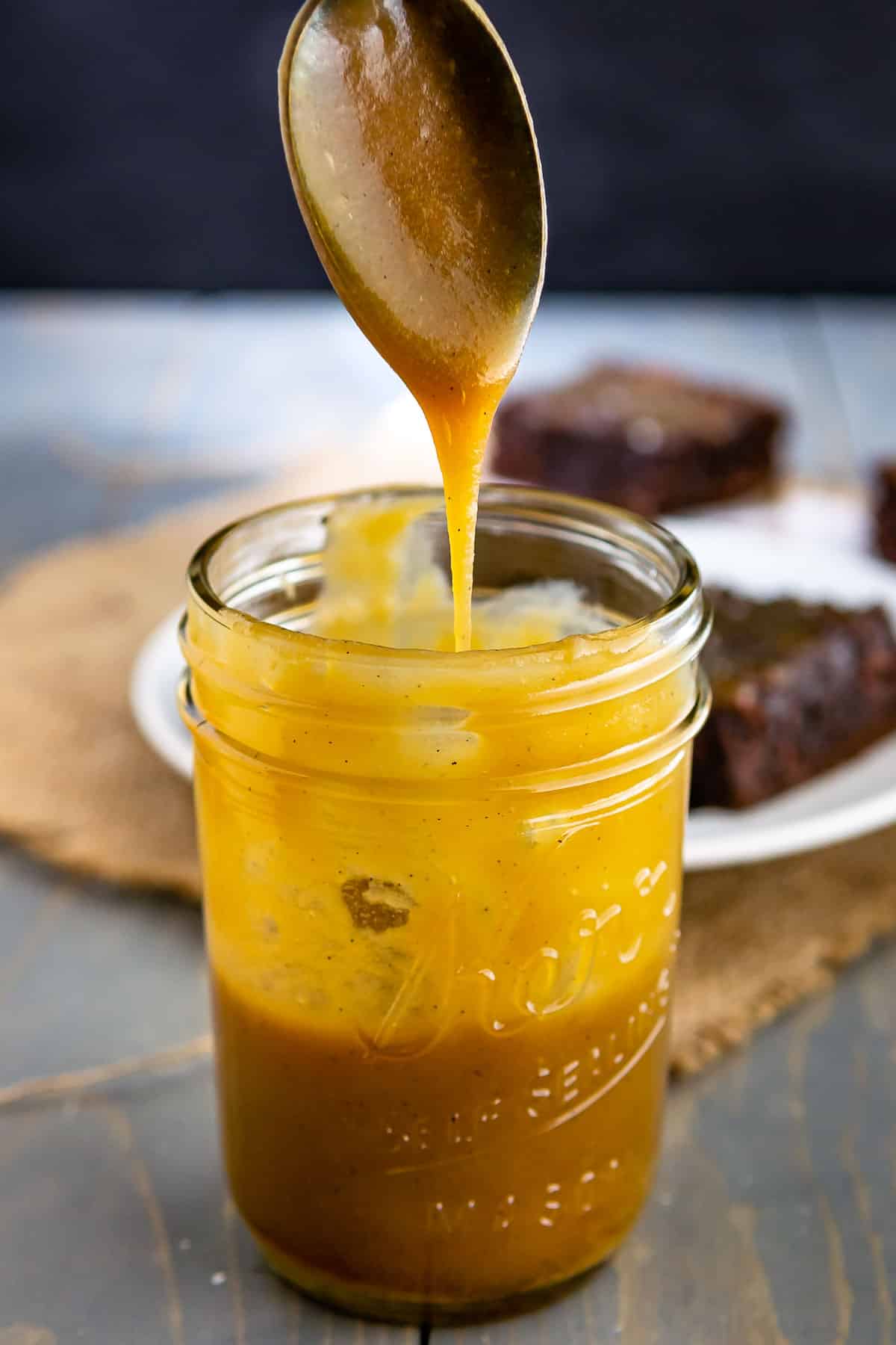 caramel in a mason jar being poured with a spoon