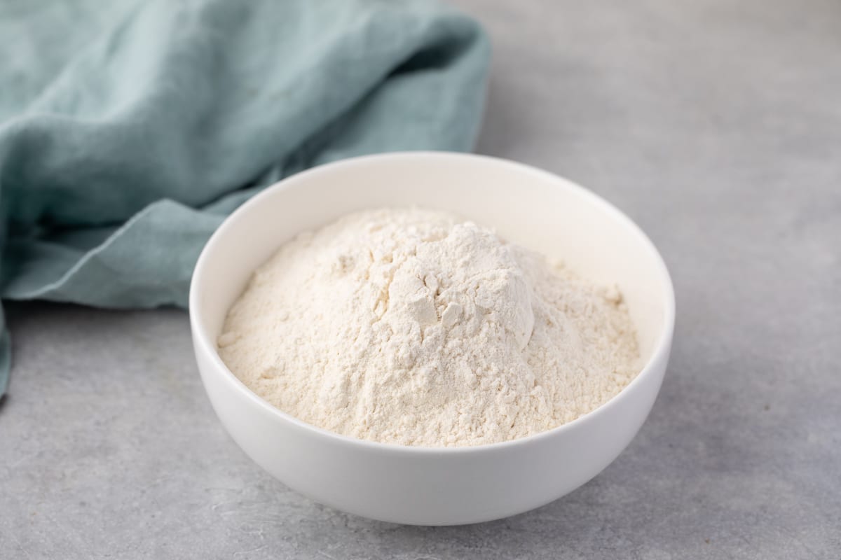 white bowl of bread flour with teal towel behind