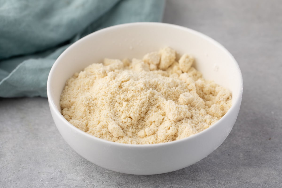 white bowl of almond flour with teal towel behind