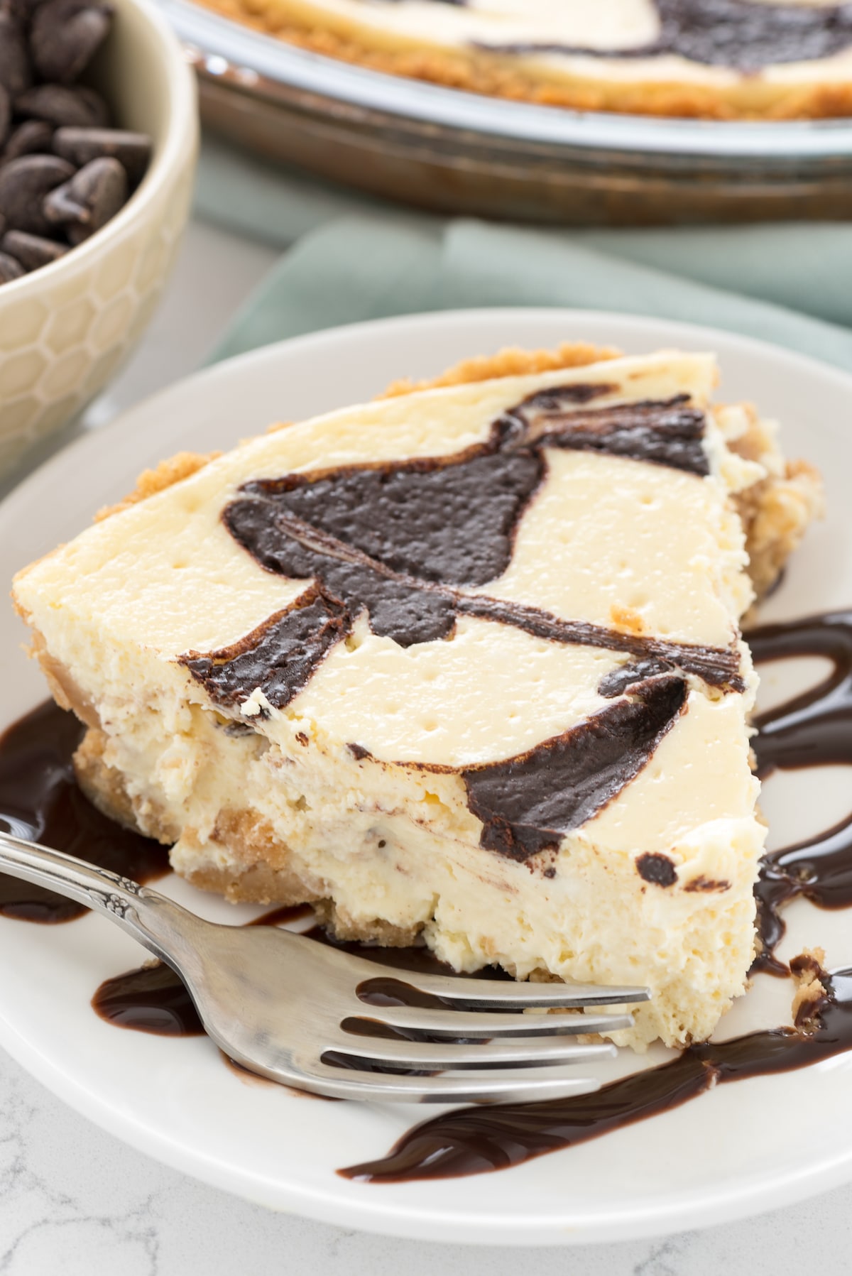 cheesecake pie on a white plate with chocolate dripped over