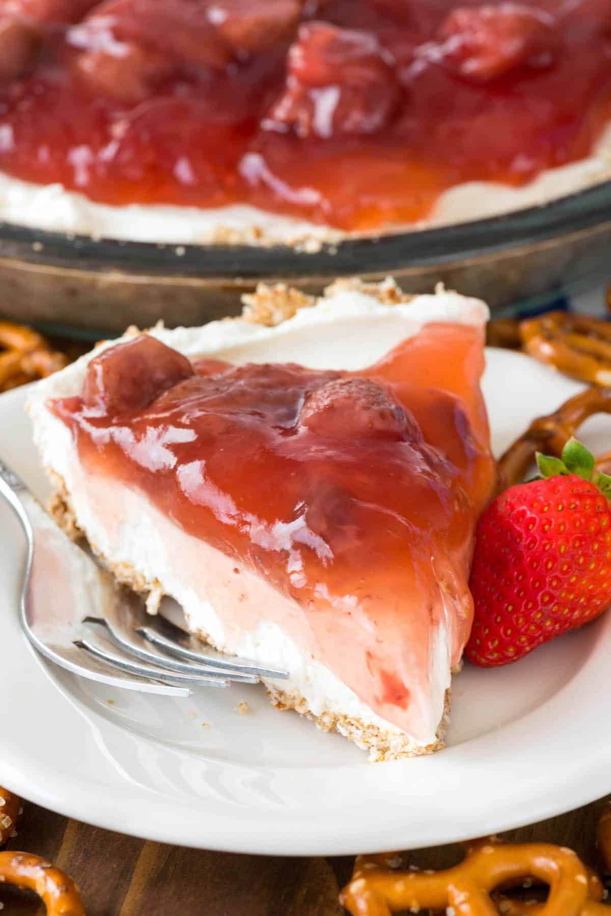 slice of cream cheese pie on white plate with strawberry topping