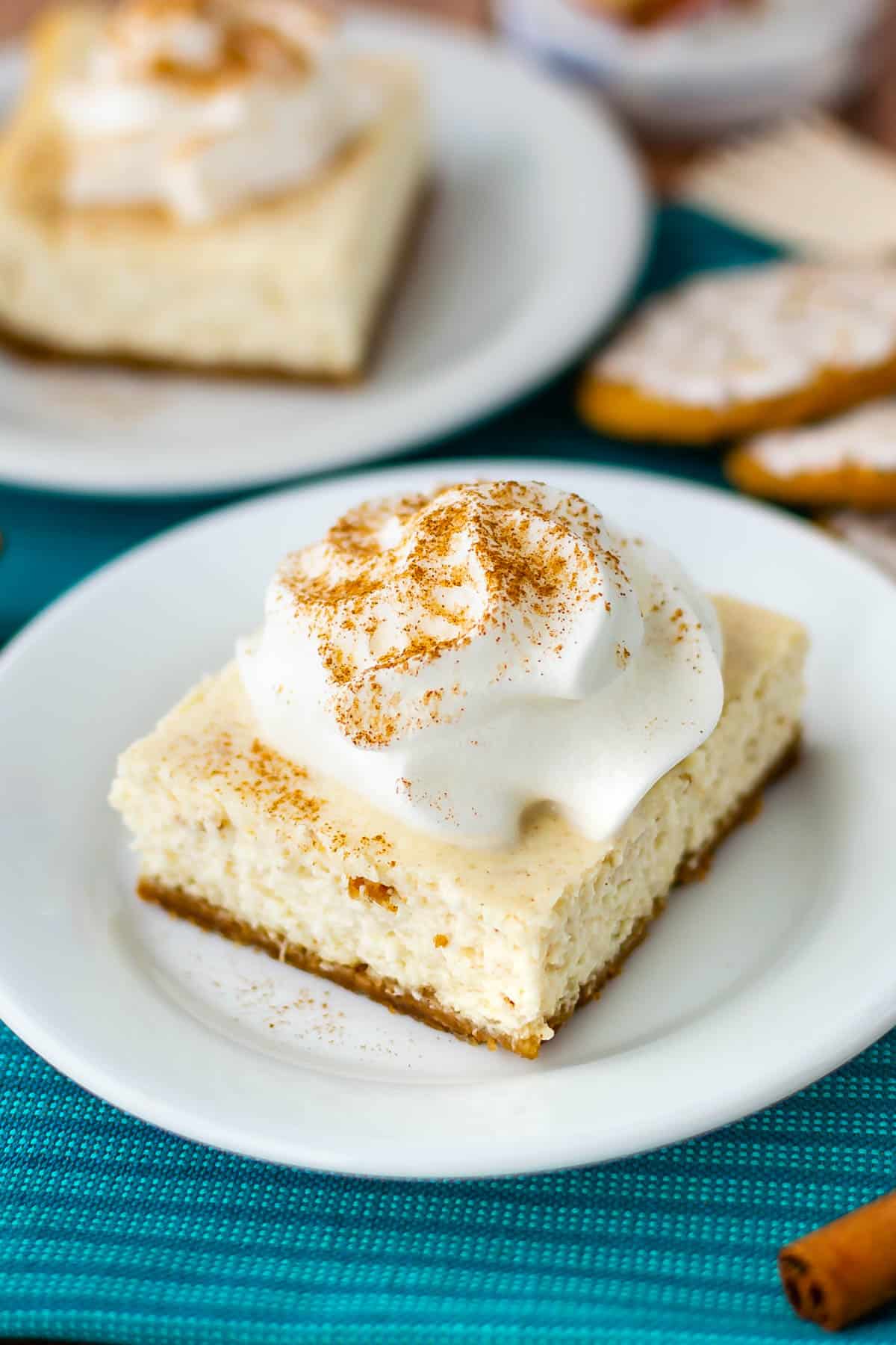 cheesecake bar on a white plate with chipped cream on top of a blue towel