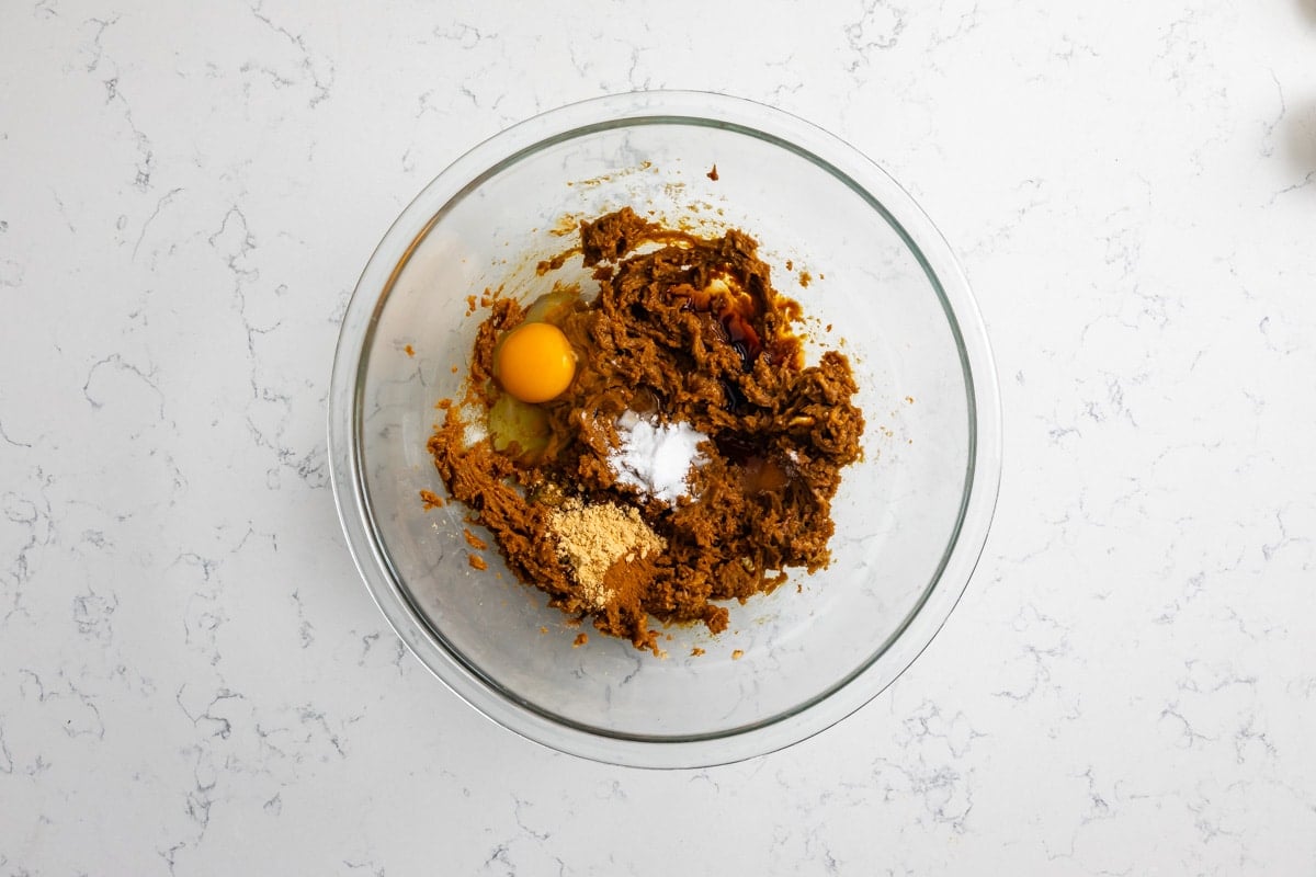 creamed butter and sugars and molasses with egg an spices in clear bowl.