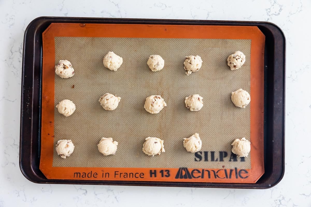 cookie dough balls on silpat lined cookie sheet.