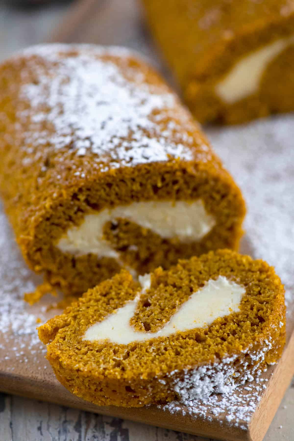 pumpkin roll dusted with powdered sugar on cutting board