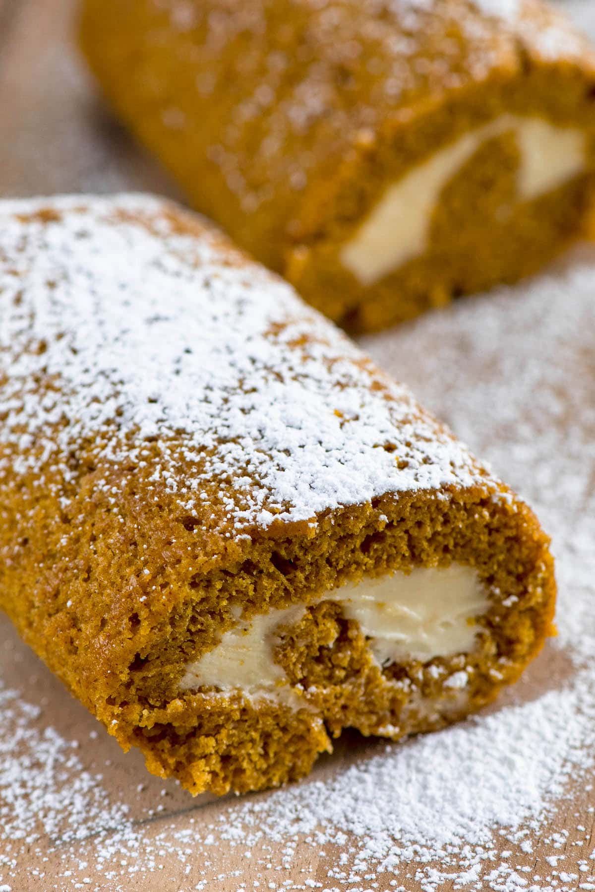 pumpkin roll dusted with powdered sugar on cutting board