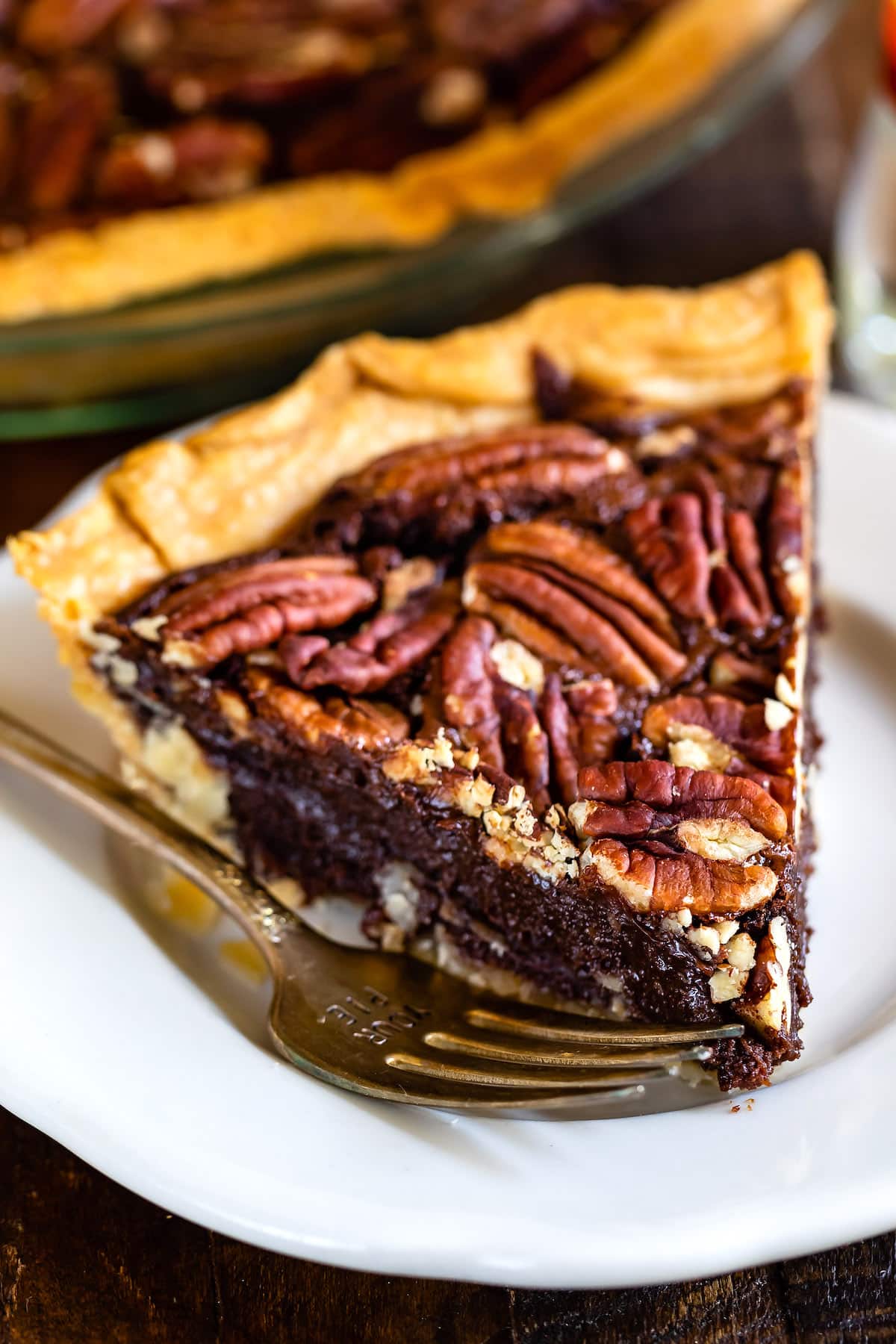 chocolate pecan pie on a white plate next to a fork