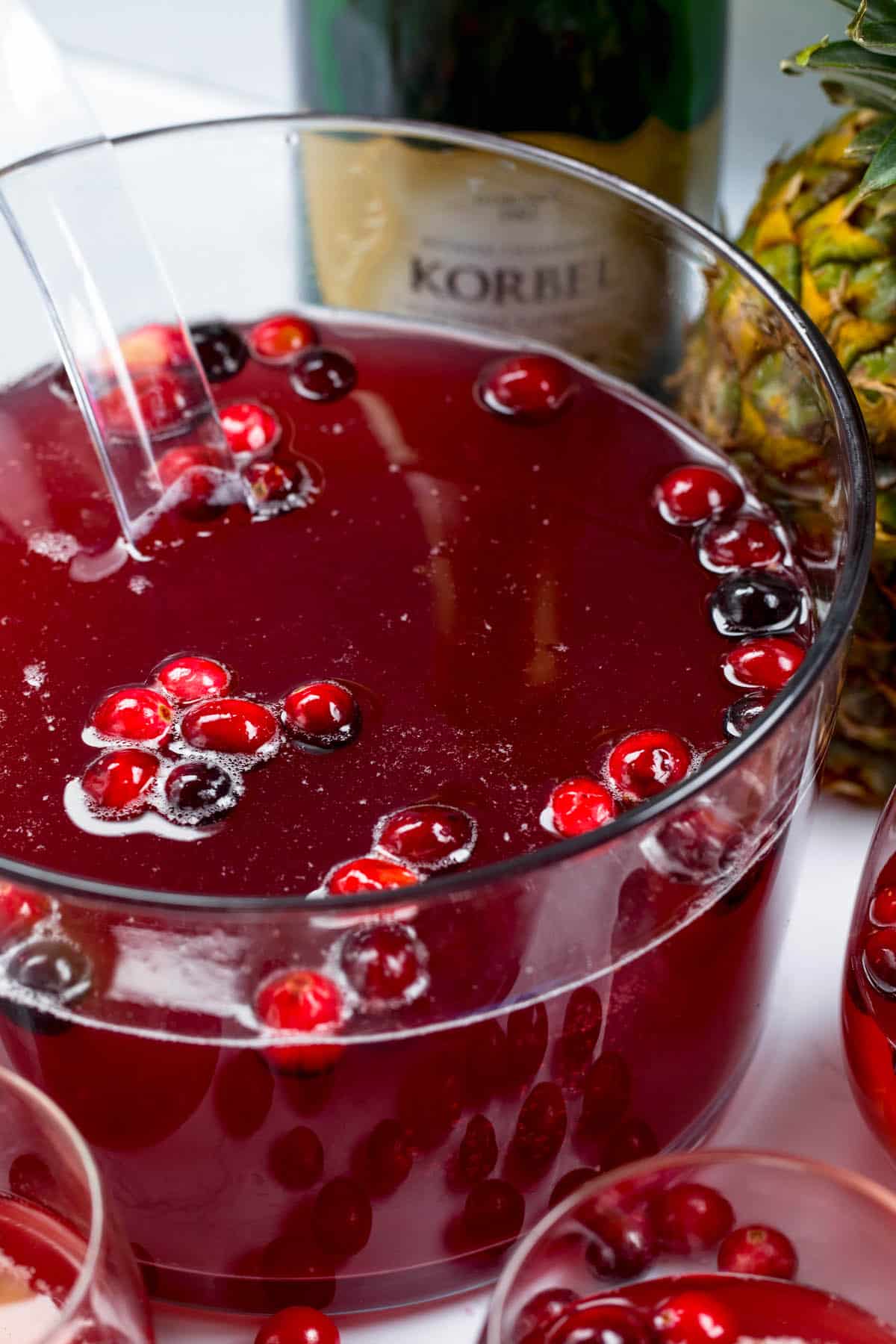red Champagne in a clear bowl with pineapple and cranberries inside