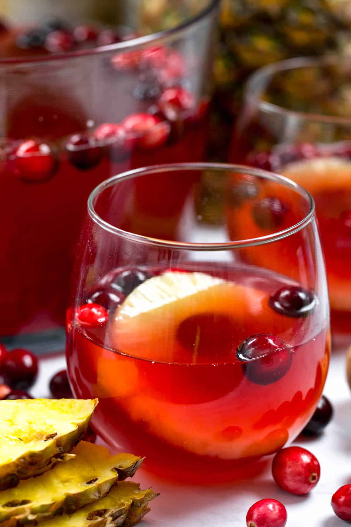 red Champagne in a clear stemless glass with pineapple and cranberries inside