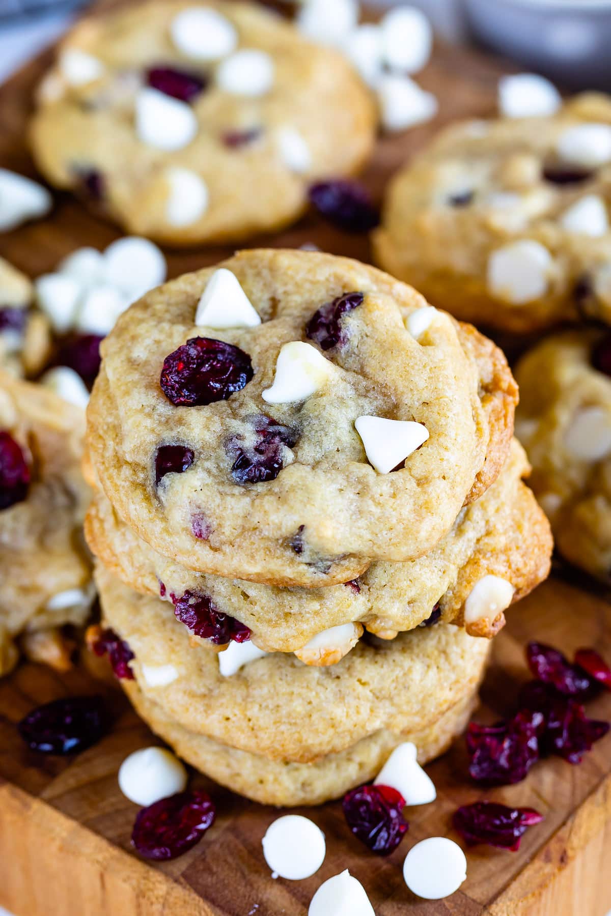 stacked cookies on a cutting board with white chocolate chips and cranberries baked in