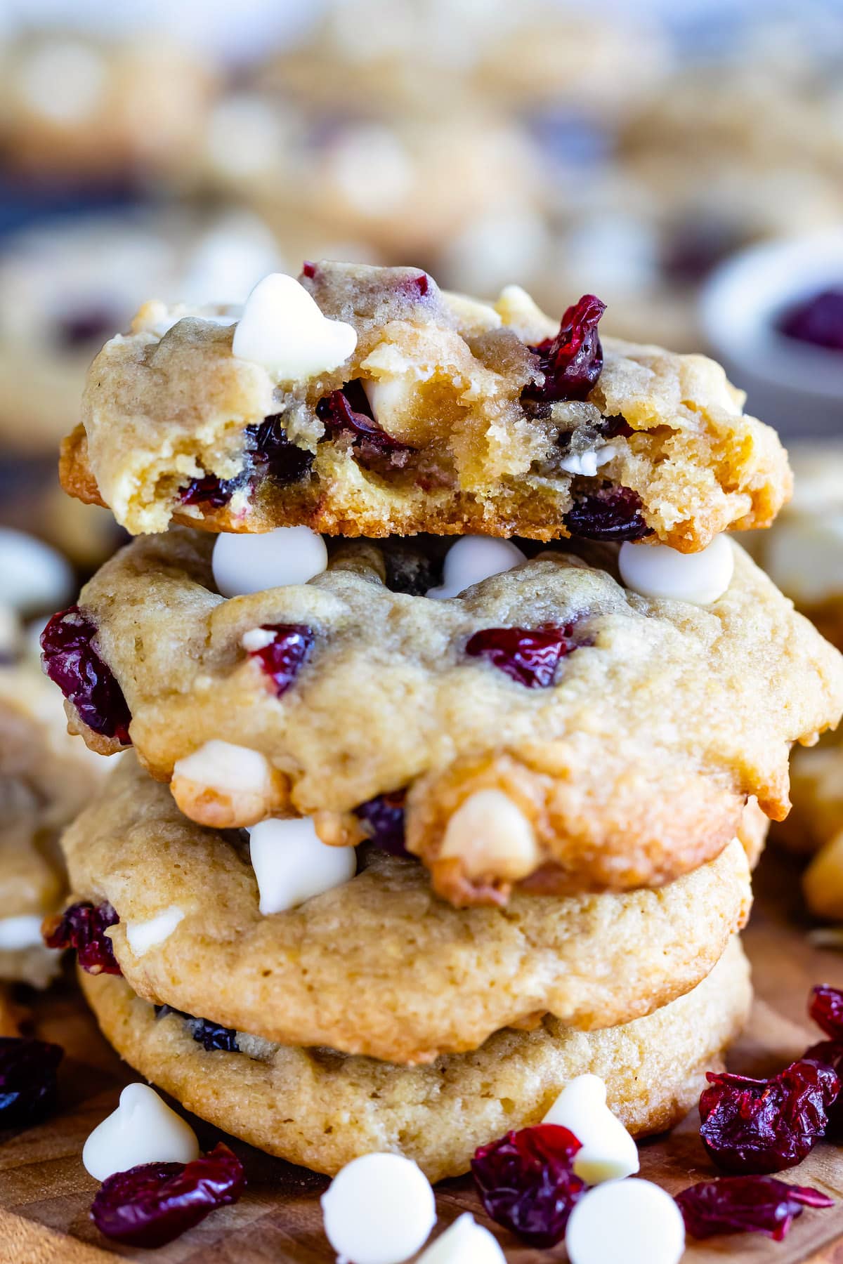 stacked cookies on a cutting board with white chocolate chips and cranberries baked in