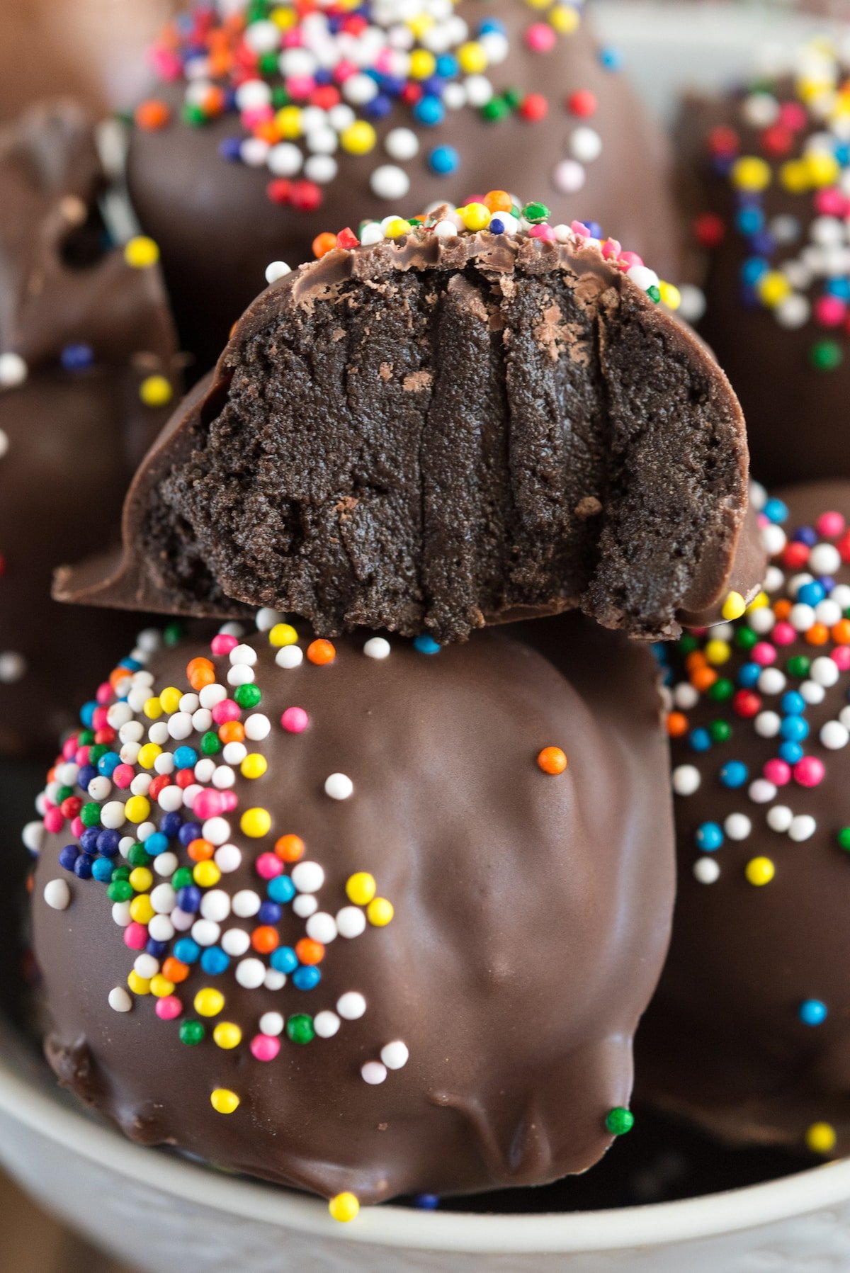 chocolate covered truffled with colorful sprinkles on top in a white bowl