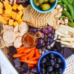 cheese board items laid on a wooden cutting board with words on top