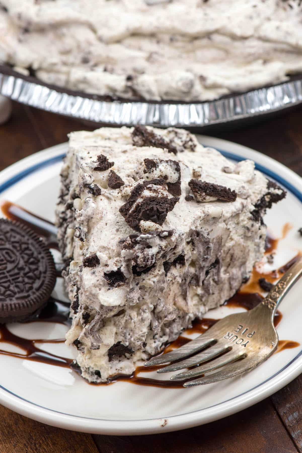 slice of oreo pie on a white plate with chocolate drizzled over top