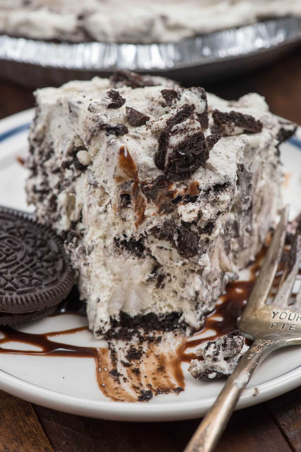 slice of oreo pie on a white plate with chocolate drizzled over top