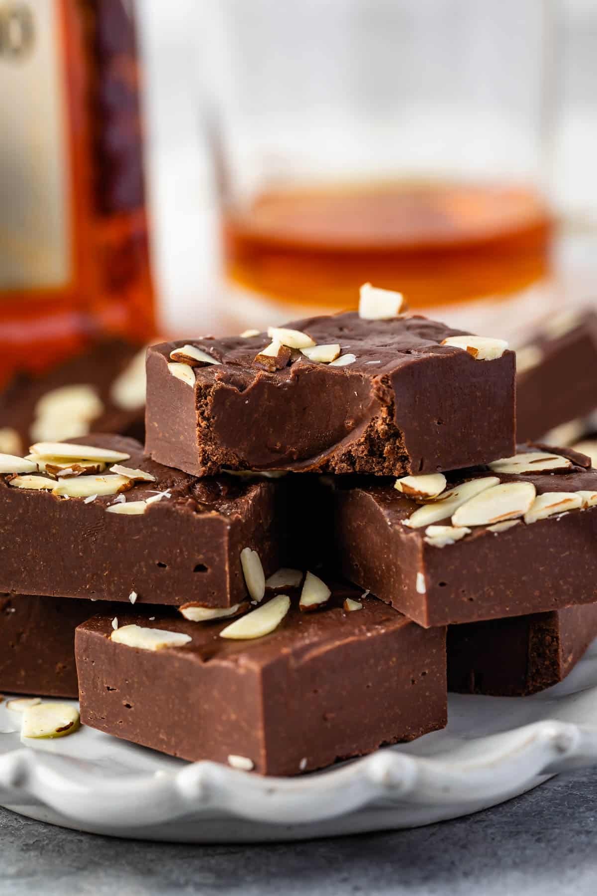 Amaretto Fudge by www.www.crazyforcrust.com | A rich and easy chocolate fudge infused with Amaretto Liquor. Perfect for an adult's only evening! #Fudge brown fudge with shaved almonds on top on a white plate
