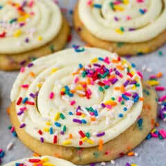 cookies with frosting and rainbow sprinkles on parchment