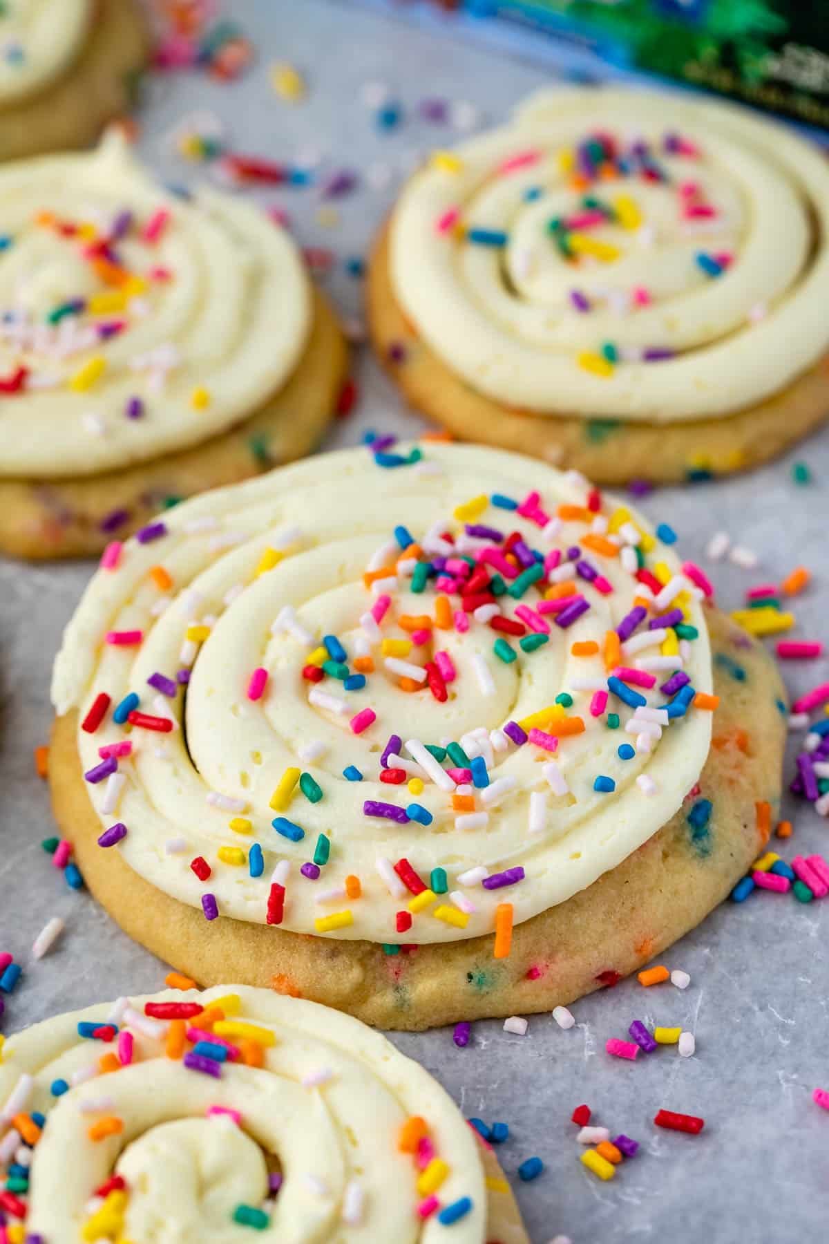 cookies with frosting and rainbow sprinkles on parchment