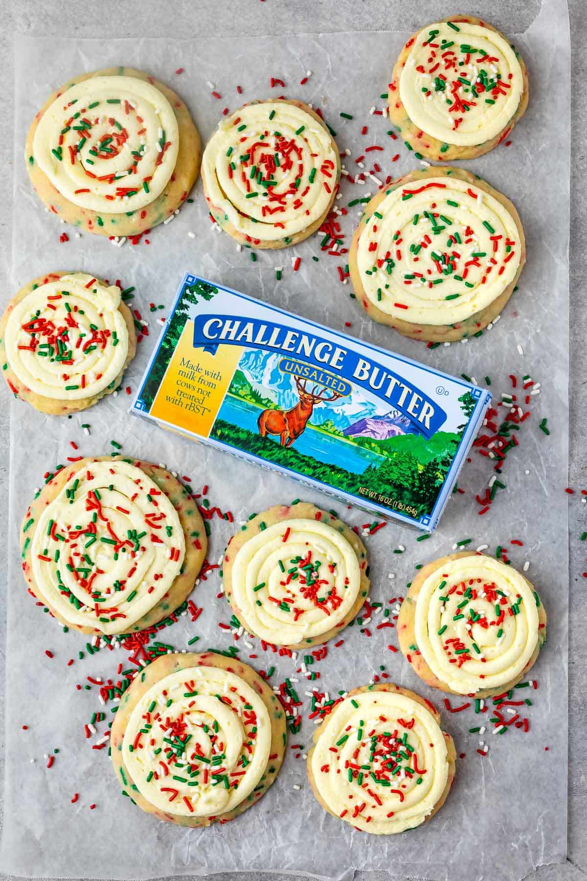 cookies with frosting and christmas sprinkles on parchment and butter box
