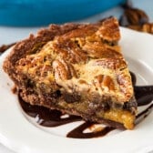 pecan chocolate pie on a white plate with chocolate drizzled over the top