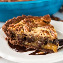 pecan chocolate pie on a white plate with chocolate drizzled over the top