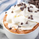 drinking chocolate in a white mug covered in whipped cream and chocolate chips