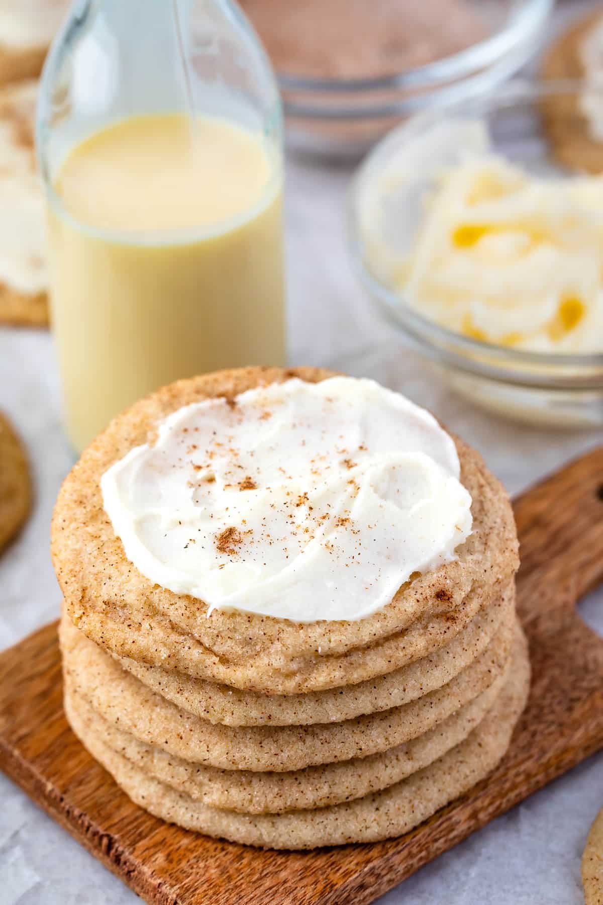 frosted eggnog cookies stacked on a cutting board