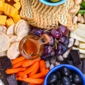 cheese board items laid on a wooden cutting board with words on top