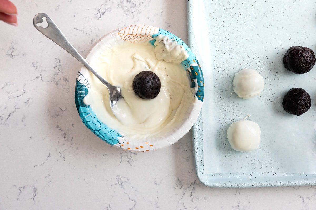 Oreo ball in bowl of melted white chocolate.