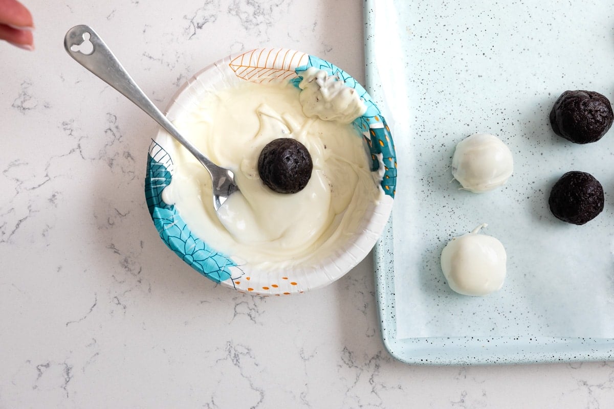 Oreo ball in bowl of melted white chocolate.