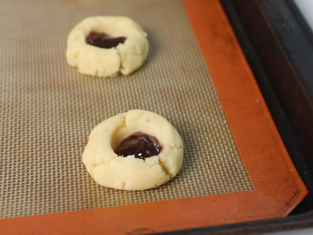 cookie dough balls with thumbprints filled with jam pn silat cookie sheet.