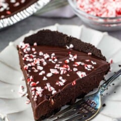 one slice of ganache pie on a white plate with peppermint crushed on top