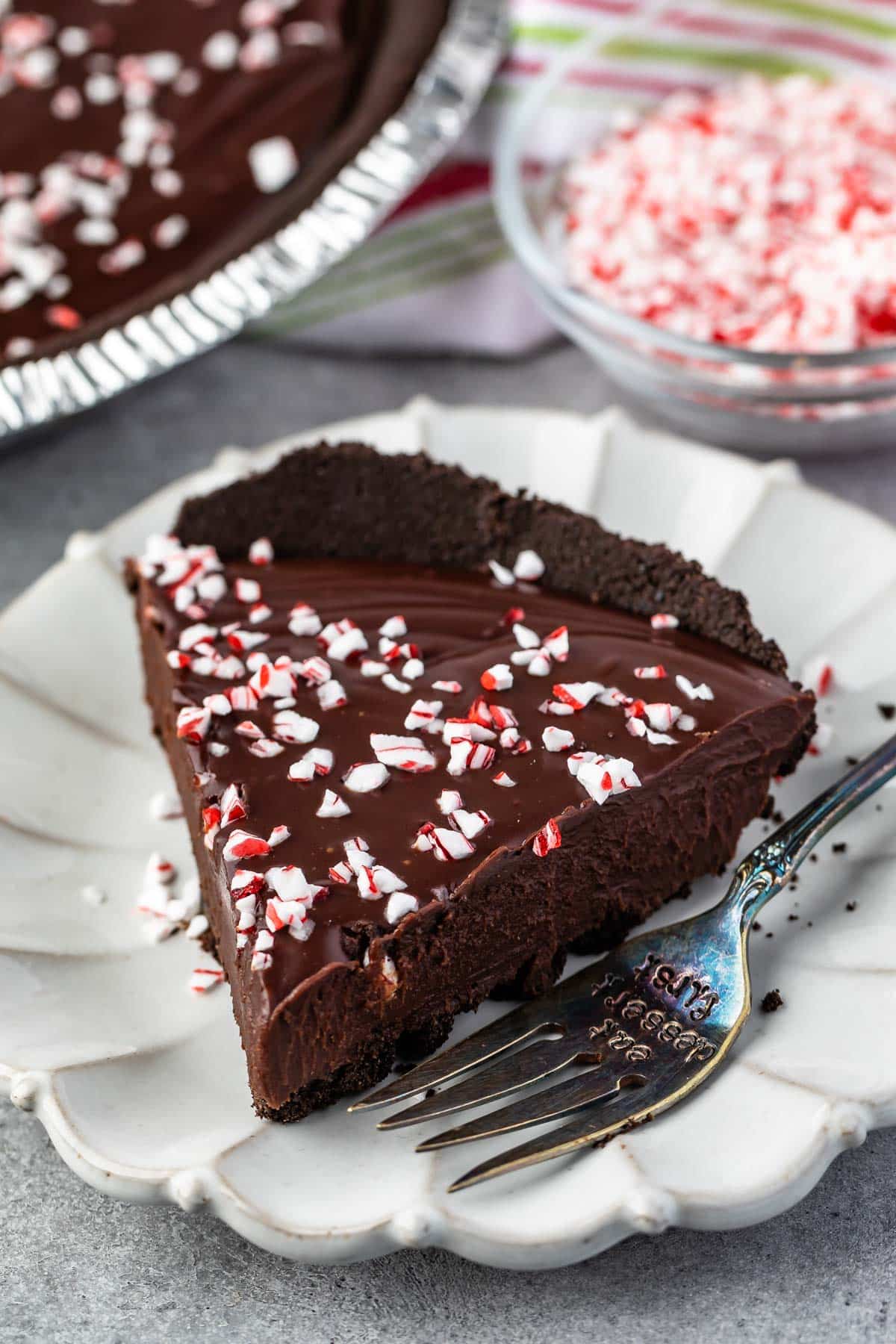 one slice of ganache pie on a white plate with peppermint crushed on top