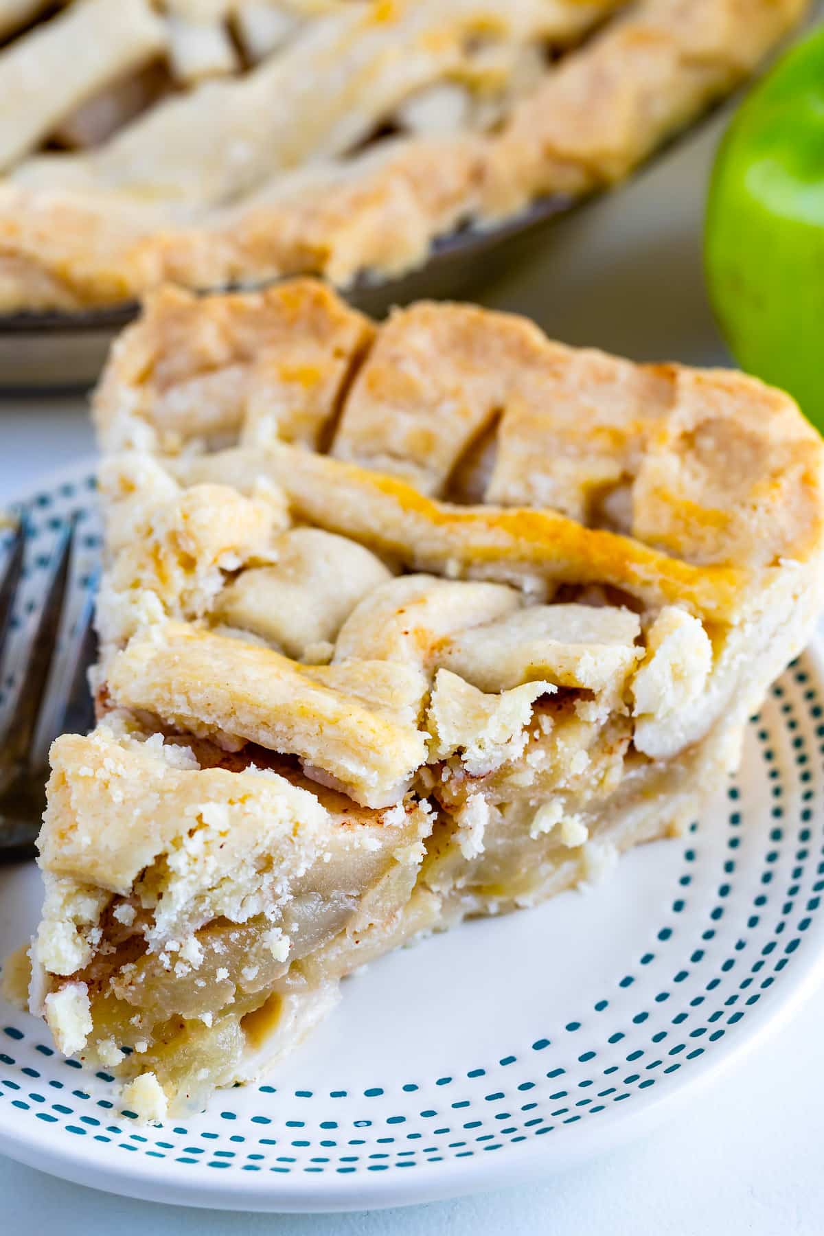 slice of apple pie with lattice top on white plate with blue stripes