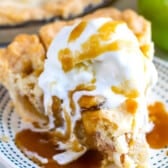 slice of apple pie with lattice top and ice cream and caramel on white plate with blue stripes