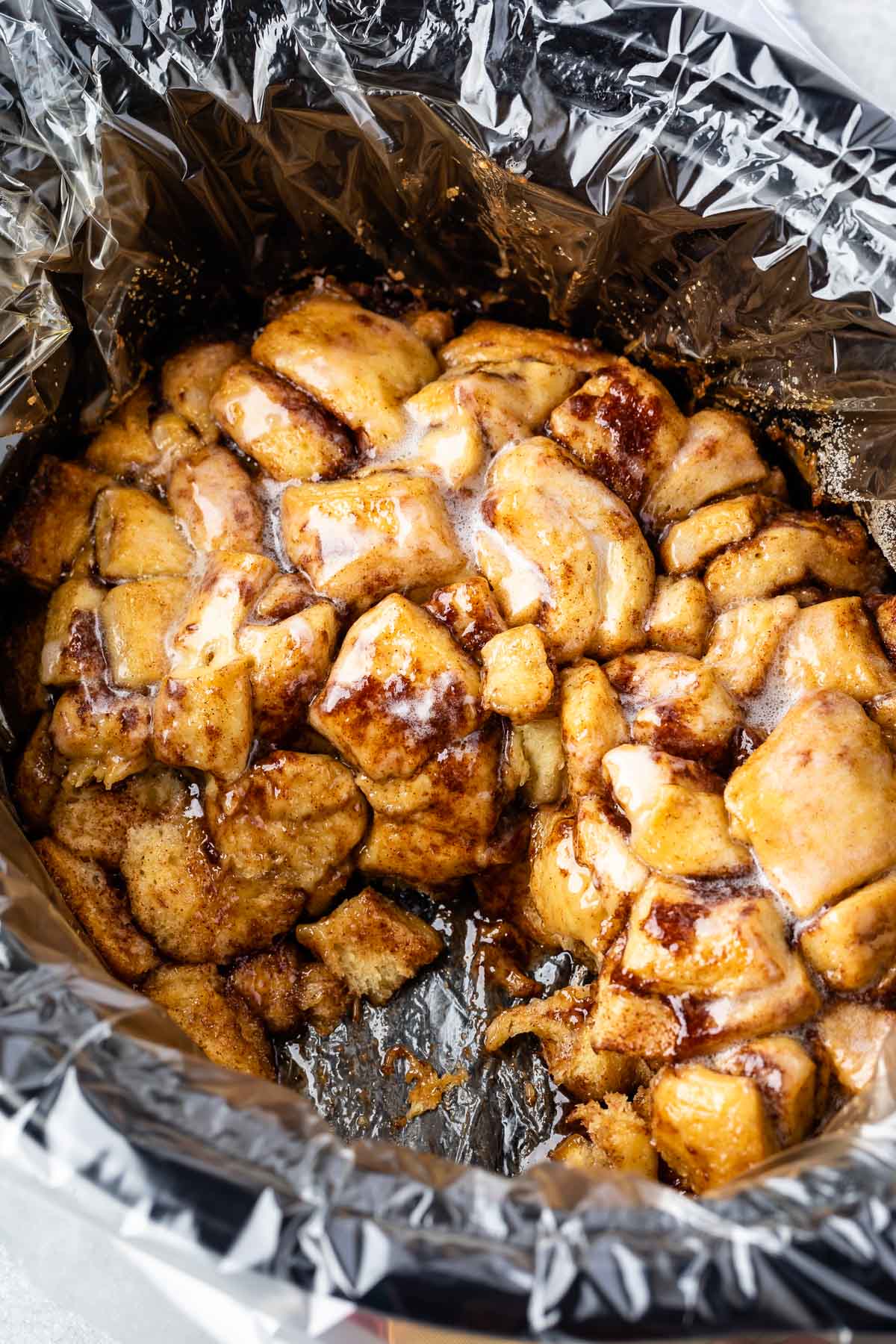 monkey bread covered in icing sitting in a slow cooker