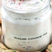 two photos of sugar cookie mix in a big clear container with sugar cookies sitting around the container with words on top