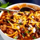chili covered in cheese in a white bowl