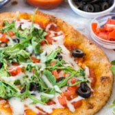 pizza with olives and arugula on top