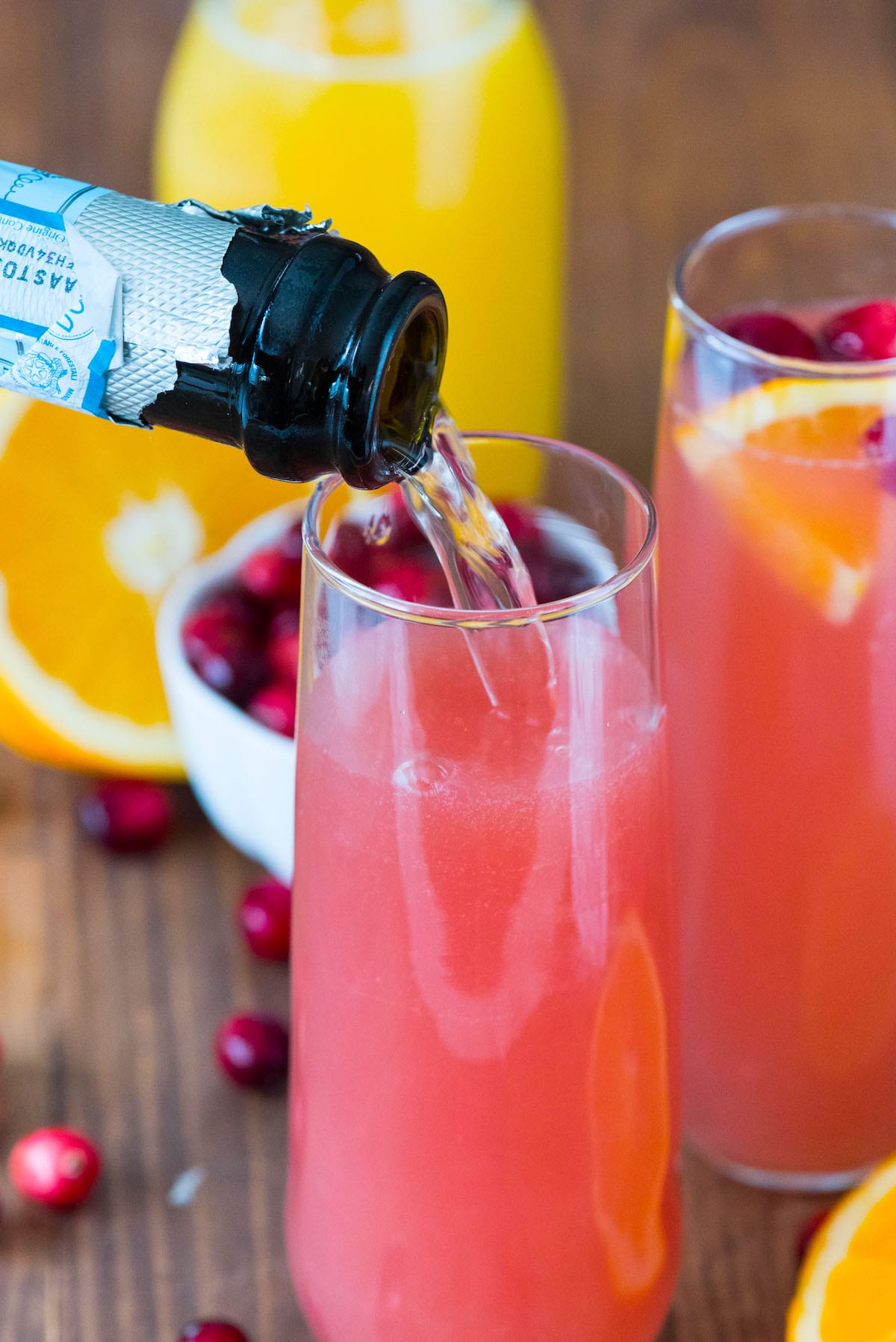 two glasses filled with pink drink with cranberries and orange slices in the glass