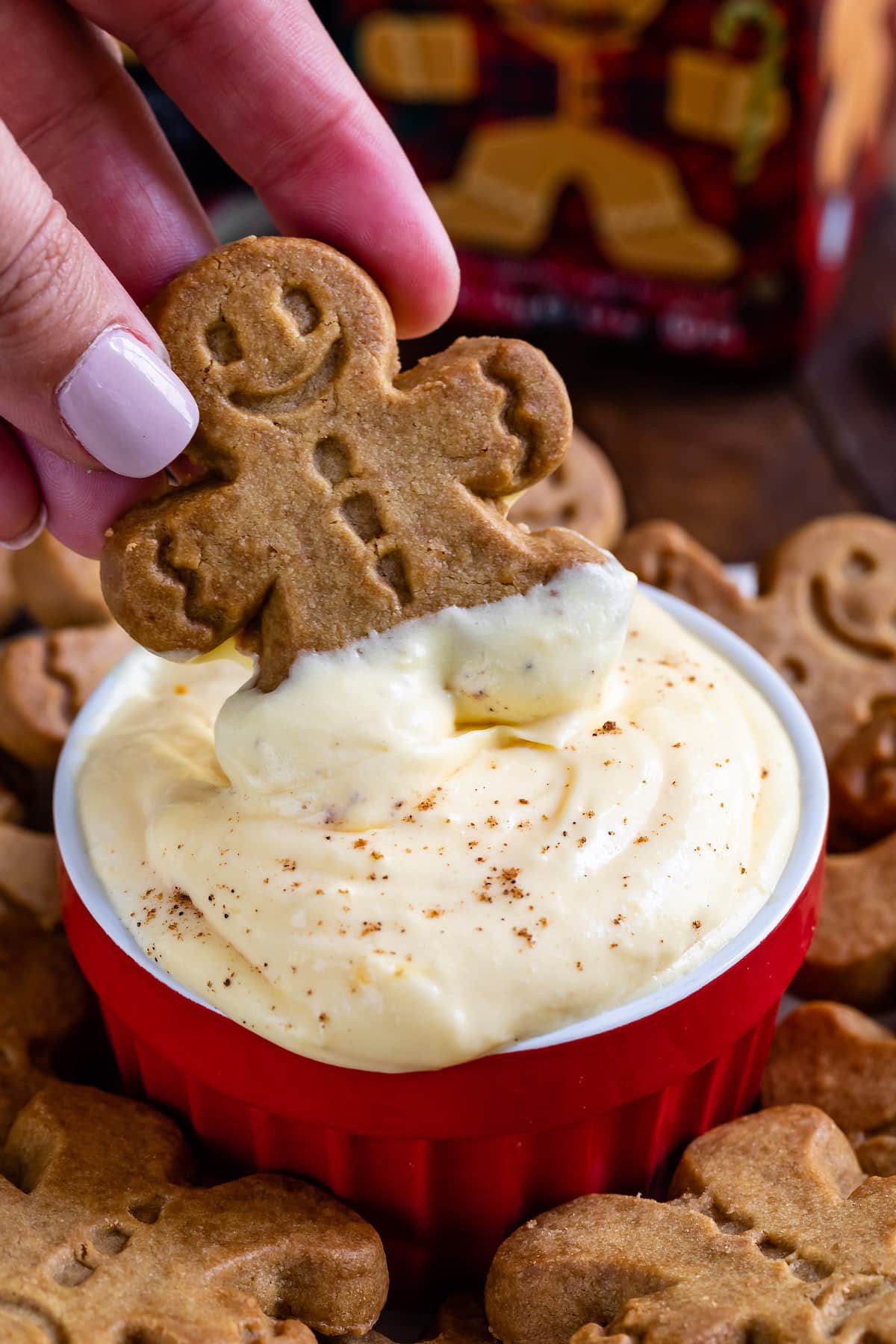 hand dipping cookie in eggnog pudding