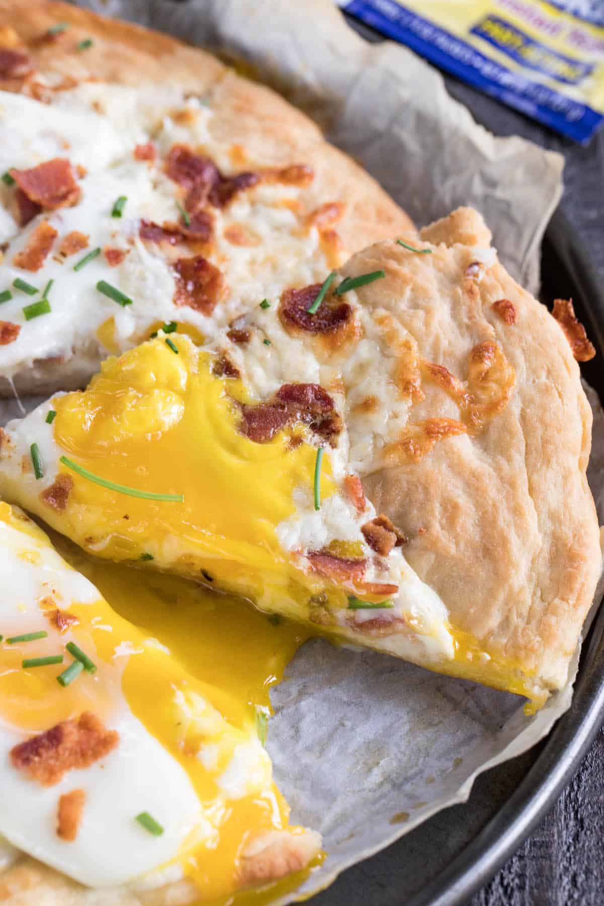 pizza with bacon and eggs on top and words on the image