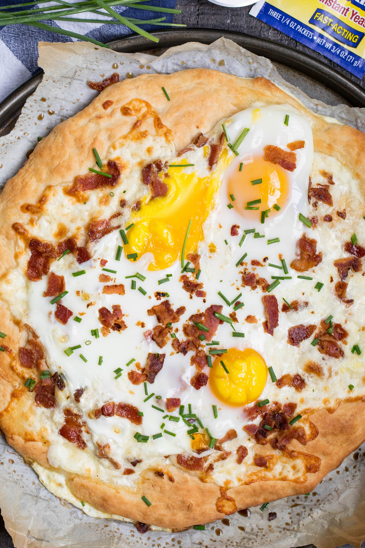 pizza with bacon and eggs on top and words on the image