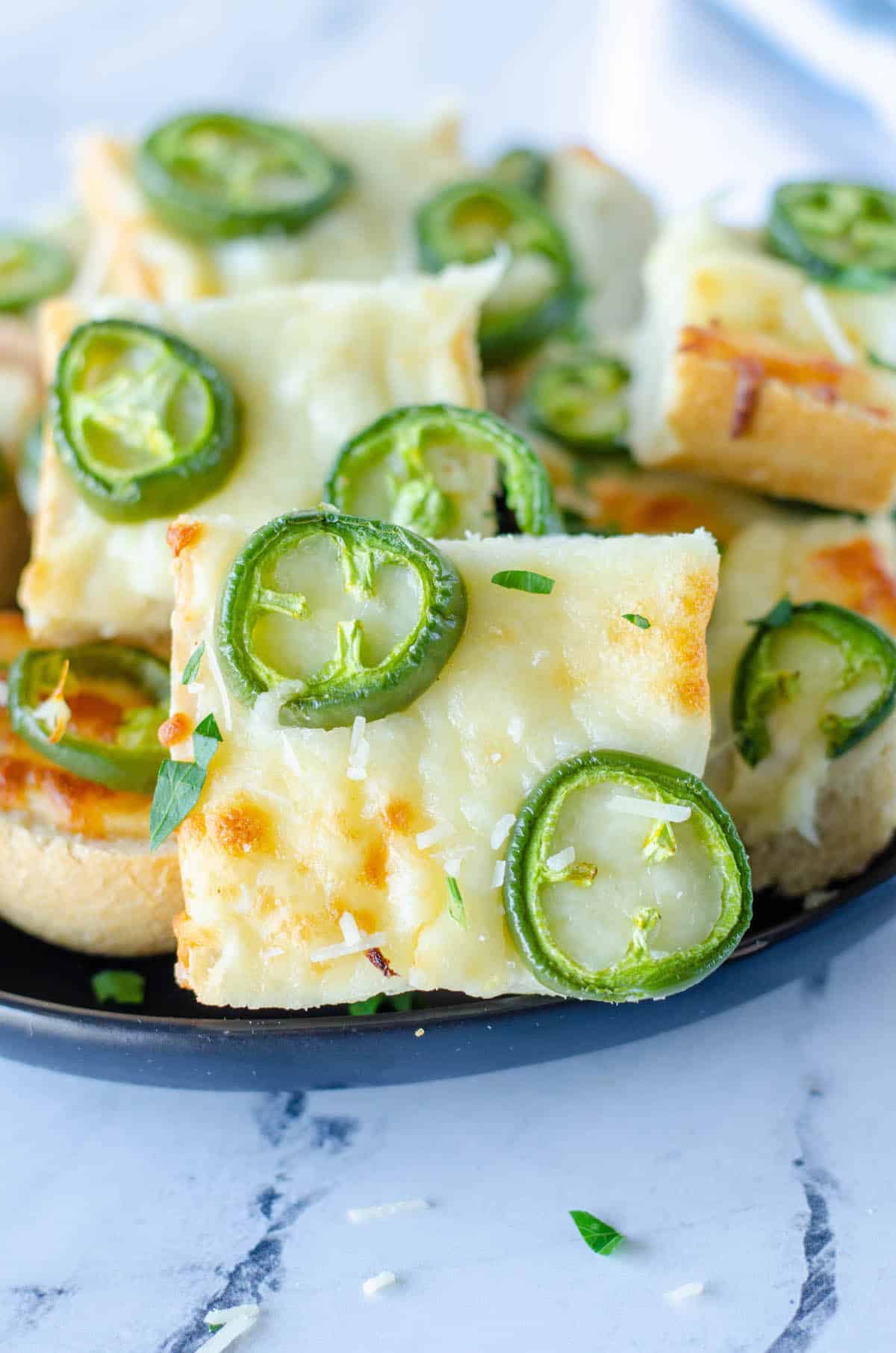 chopped bread with jalapeños on top on a cooking sheet