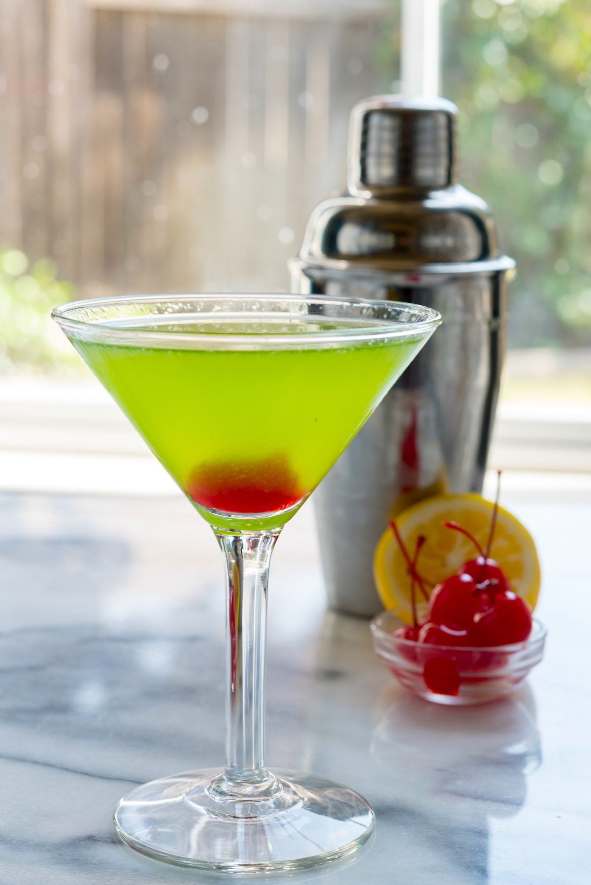 green martini with red at the bottom in a clear glass