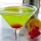 green martini with red at the bottom in a clear glass