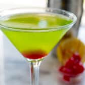 green martini with red at the bottom in a clear glass