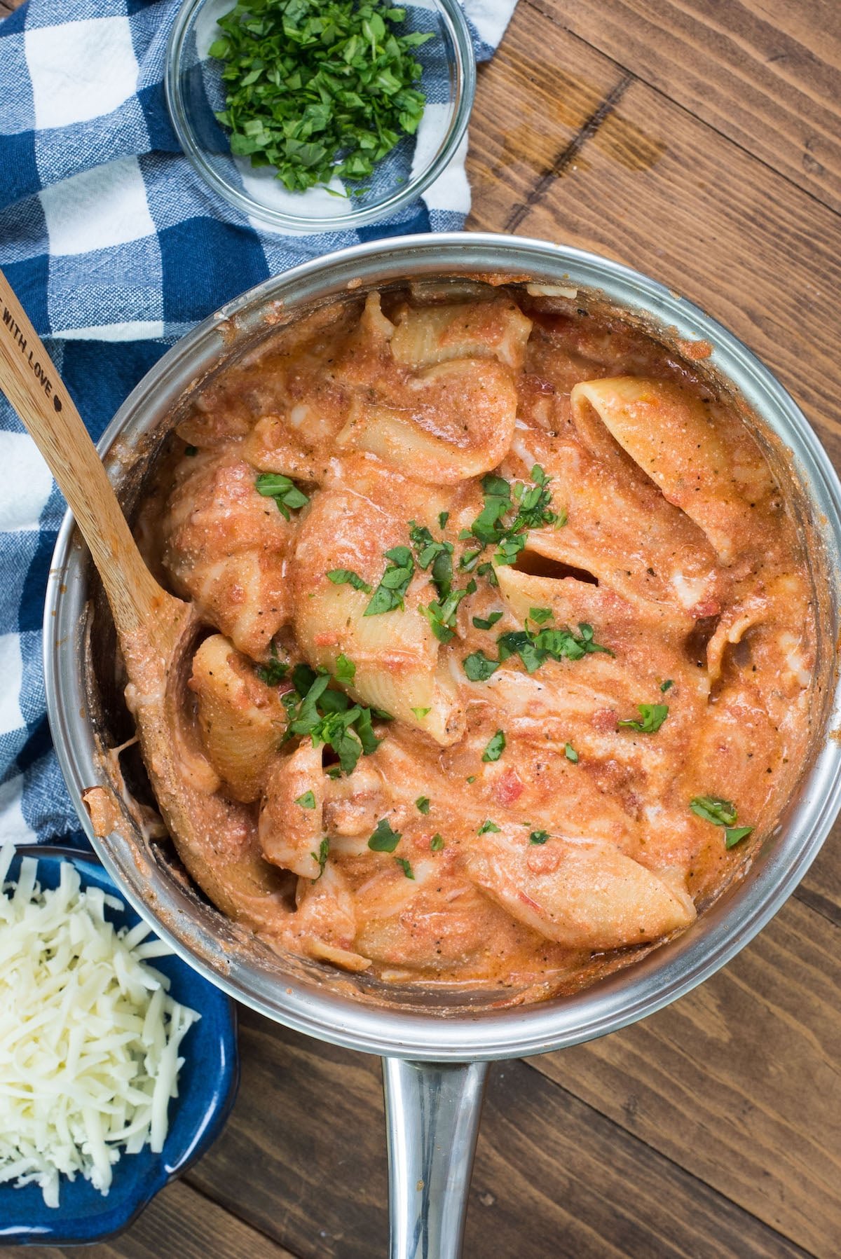 pasta covered in sauce in a metal pan with a wooden spoon