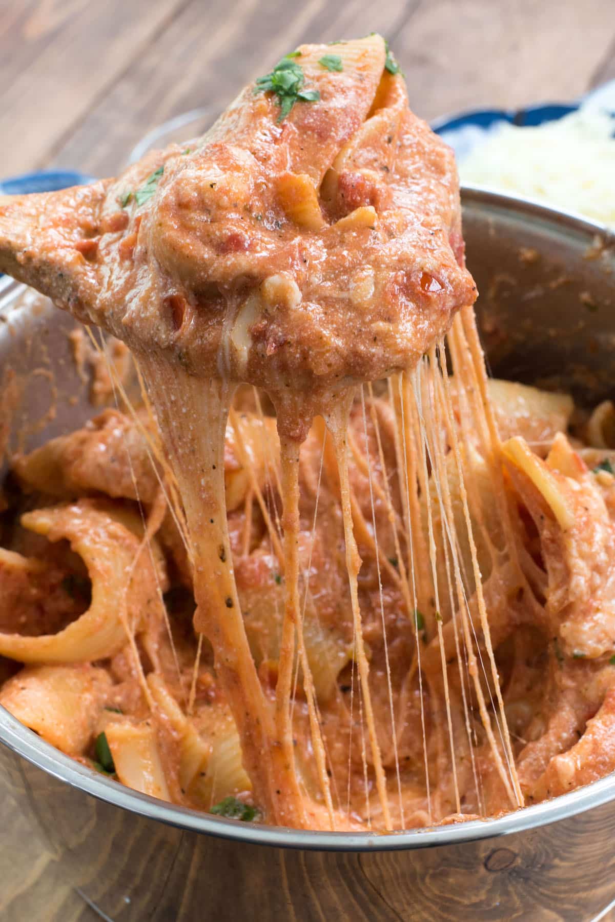 pasta covered in sauce in a metal pan with a wooden spoon